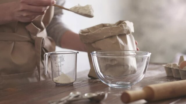 The hostess chef sprinkles flour into a measuring cup with a spoon. Dough preparation step by step. The process of preparing hand dough ingredients from flour. Knead the dough for baking. 