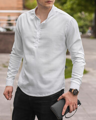 Stylish handsome model man in casual clothes lifestyle in the street with watch and leather clutch