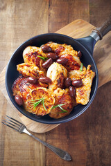 Grilled chicken pieces with kalamata olives and fresh rosemary. Rustic wooden background. Top view. 