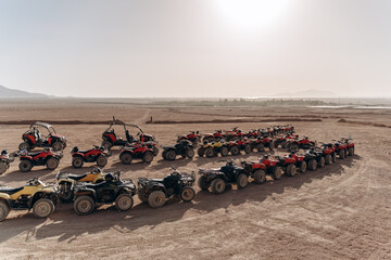 Large column of ATVs and buggies stands in the middle of a sandy desert. Ready for fun in the desert