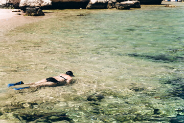 Girl swims with a mask in the sea. Young, slender girl looks at beautiful coral reefs