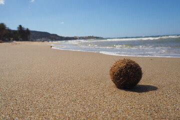 Mała beżowa kulka na piasku na tle morza i fal, Grecja, Kreta