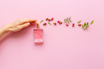 Female hand spray perfume bottle and flow of flowers