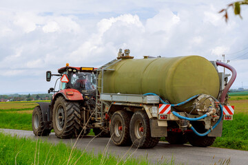 Water tank for tractor trailer. Modern tractor with a cistern tank, on an asphalt road near agricultural fields. © Yaroslav