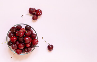 cherry in the plate stands on a pink background with copy space. summer background with fruit cherries