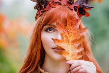 fairy woman with deer horns in autumn forest. Face painting. Beautiful mystery woman. redhead girl with big eyes magical sight