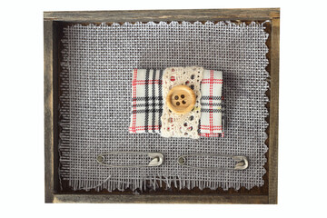 small sewing kit composition. button, fabric and safety pin in wooden box
