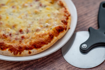 Close up and selective focus of a home cooked thin crust four cheese pizza on a white plate on a wooden table