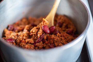 Close up and selective focus of a meat chilli concarne cooking on the hob in a stainless steel...