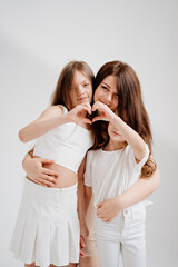 Mom cuddles with her daughters. hands are folded in the shape of a heart