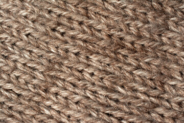 Diagonal close up of a large knitted jumper. Jersey stitch. Natural colours, heathered beige.