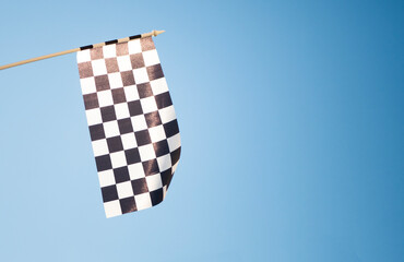 Сheckered flag on blue sky background. Start or finish signal. New beginning concept. Copy space