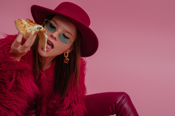 Fashionable woman eating pizza. Model wearing  trendy green cat eye sunglasses, hat, burgundy color...