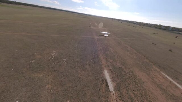 View from above flying airplane on runway at nature field near small village countryside. Shooting from sport fpv drone plain craft raising over amazing natural landscape at farmland sky horizon