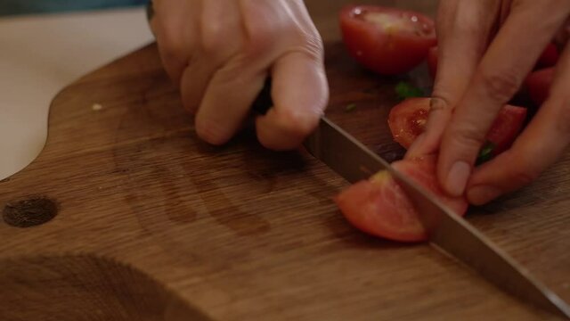 female hands slicing tomatoes in home