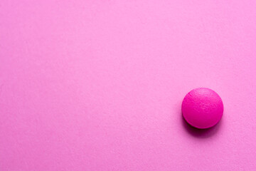 Pink tablet on a pink table close-up. Medical theme.