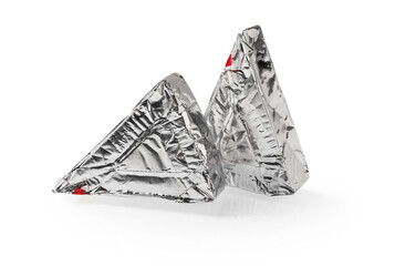 Two triangular pieces of foil wrapped processed creame cheese isolated on a white background. Tasty soft cheese in a silver aluminium foil. Sandwich ingredient. Macro.