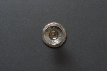Obraz premium isolated, worn and tarnished silver candlestick holder viewed from above with focus on the interior - or metal circles on grey board