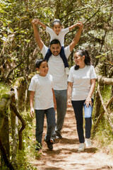 Happy hispanic family walking in the natural park - young parents with their children in the park -latin family