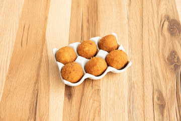 Tapa of Spanish iberico ham croquettes inside a plate that resembles an egg cup