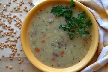 Bean soup in yellow plate, next to beans on wooden table top view