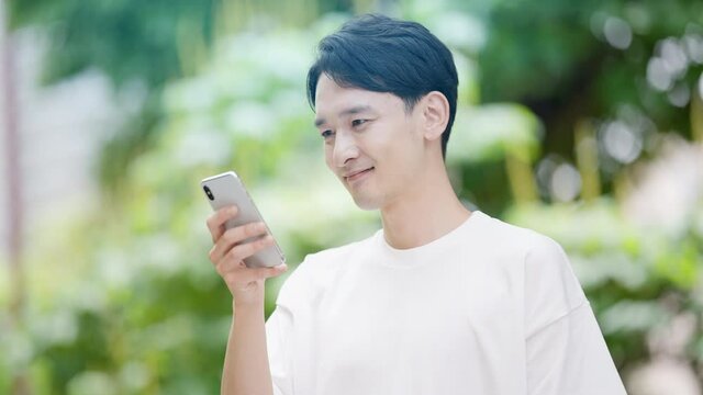 屋外でスマートフォンを使う若い男性