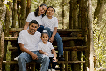 Hispanic family enjoying nature in the park - young parents with their children outdoors smiling at...
