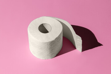 roll of a white toilet paper isolated on a pink background close-up. hard shadows from the sun at noon