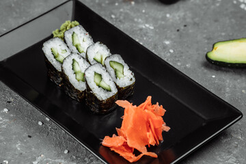 Delicious, juicy and mouth-watering maki with cucumber. Sushi on a gray background