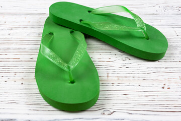 green rubber flip-flops on a white wooden background