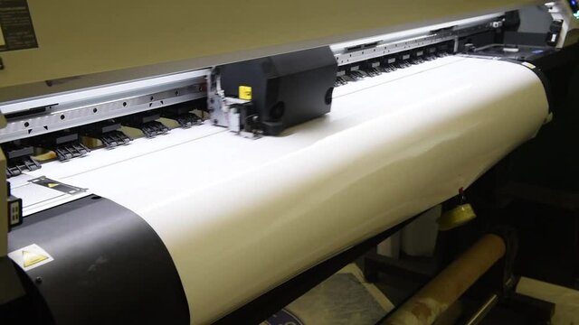 Large Format Printing Press Prints Outdoor Advertising Posters In The Production Shop. A Roller With A Roll Of Paper Is Fed For Printing In Plotters