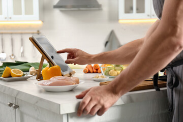 Man watching online cooking course via tablet in kitchen, closeup