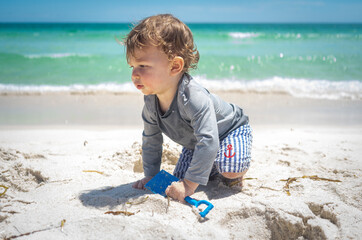 Baby beach adventure on family Florida road trip with white sand and blue ocean water crawling with sailor shorts and shovel