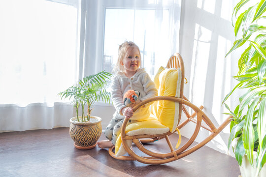 Defocus. Girl todler sits in a rocking chair in the sun. Candid people concept.