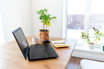 Defocus. Black cup with coffee stands a wooden table next to a laptop. Concept slow life.