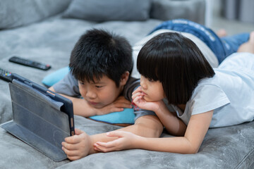 two chinese children addicted tablet, asian child watching telephone together on their bed, kid using smartphone