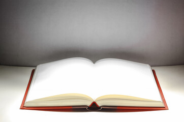 A book that looks like a Bible open in dark and red color background with very bright golden light on the page. Spiritual Life concept.