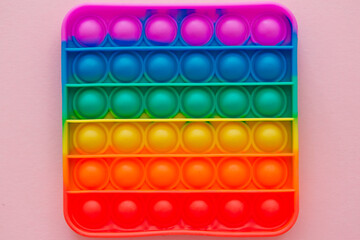 Colorful antistress pop it toy on the pink background.