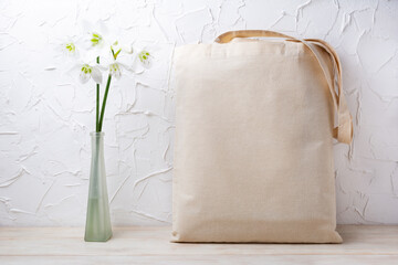 Rustic tote bag mockup with white lilies in the vase