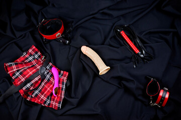 A set of erotic toys for adults. Red plaid skirt, dildo, vibrator, collar, handcuffs, whip. Sex...
