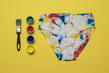 Paint and painted women's panties in the style of tie dye on a yellow background.