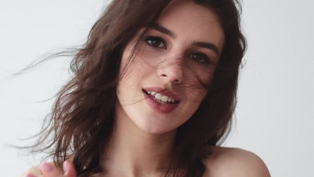 Beauty care. Facial treatment. Special offer. Wellness health. Surprised smiling brunette woman with pretty face nude makeup flying hair in wind wow reaction isolated on light.