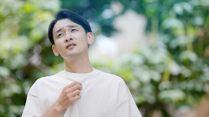 屋外で暑がる若い男性