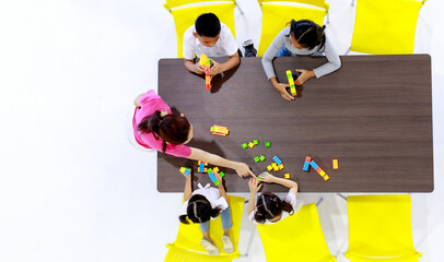 Top view shot of Asian daycare babysitter playing colorful English alphabet letters toy together on...