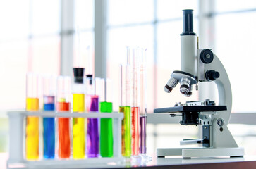 Closeup shot of three lens microscope scientific equipment on laboratory table with colorful...
