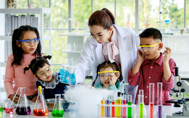 Group of Asian elementary little boy and girls wear safety goggles excited and looking at female...