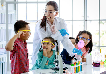 Asian female teacher in white lab coat safety goggles rubber gloves laugh do experiment with water...