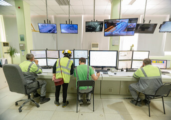 Workers in special clothes against the background of monitors, monitor technological processes....