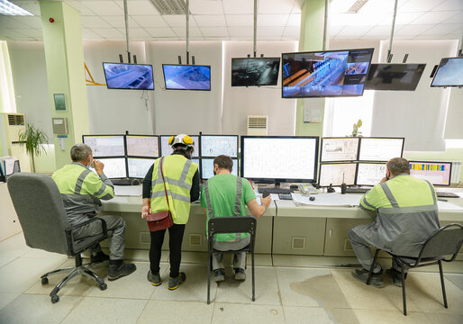 Workers in special clothes against the background of monitors, monitor technological processes. Technological works for the production of cement. Working atmosphere with copy space.