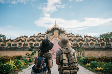 Behind two female traveler wearing a hat with backpack travel in the attraction architecture pagoda...